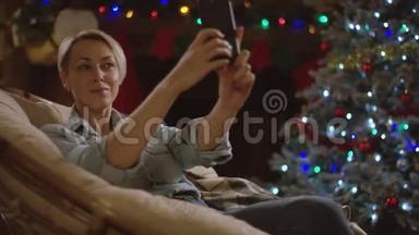 在圣诞夜，金发女人在智能手机上自拍