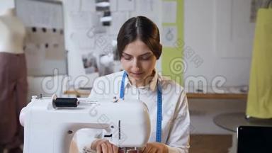 年轻的女裁缝在缝纫工作室里做缝纫机。