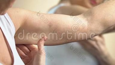 年老的女人看着手臂上的皮肤，照顾自己，衰老的变化