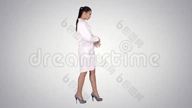 年轻的女药剂师穿着白色长袍，穿着制服，走在渐变的背景上。
