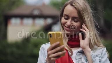 年轻美丽的女人在智能手机上使用应用程序的肖像，在手机上微笑和发短信。 穿红色衣服的女人