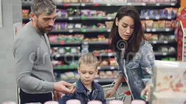 年轻的家庭母亲，父亲和孩子，在<strong>食品店</strong>里选择糖果，拿着产品，然后看着它们