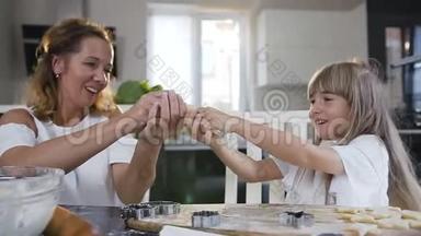 玩耍的妈妈和女儿在家里的厨房里一起烤饼干时，用面团做胡子。 妈妈和
