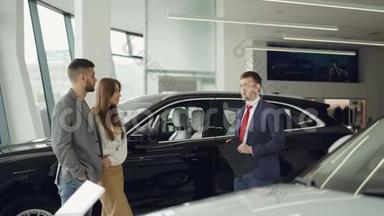 汽车经销商的工作人员正站在豪华轿车旁与一对漂亮的<strong>大胡子</strong>男和他迷人的妻子交谈