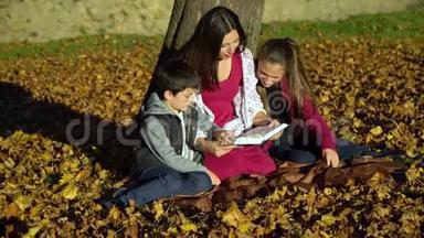 妈妈和<strong>孩子</strong>们坐在树下<strong>看书</strong>。 秋天森林里的妈妈和<strong>孩子</strong>们.. 他们很开心。