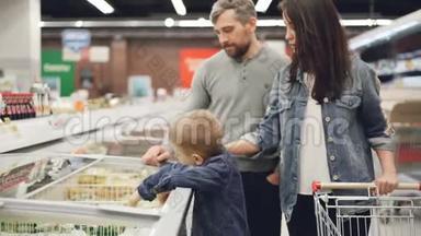 小男孩正在<strong>打开冰箱</strong>，拿着一包冷冻蔬菜，然后在买东西的时候把它