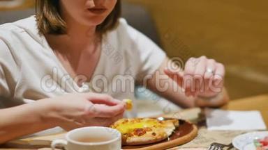 女人在一家有白种人美食的餐馆吃午饭。 特写镜头。 女人吃热汁多的卡查普里，蘸一块