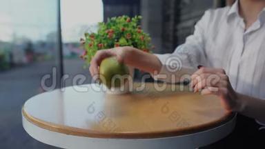 女孩把维生素丸从桌子上扔下来，然后坐在露台上吃一个绿色美味的苹果