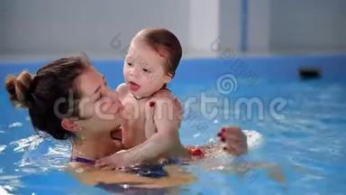 美丽<strong>的妈妈</strong>教可爱<strong>的</strong>宝贝女孩如何在游泳池<strong>里</strong>游泳。 孩子和<strong>妈妈</strong>在水<strong>里</strong>玩。