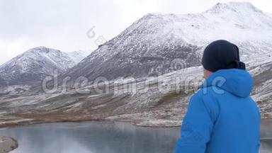 旅行者站在山湖的岸边，欣赏山的倒影。 <strong>天气晴朗</strong>。