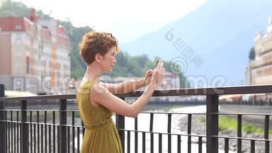 一位美女在城市背景下的智能手机上自拍。 旅游、游客、夏季