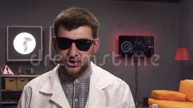 有胡子的科学家戴着太阳镜和白色的实验室外套解释事情。
