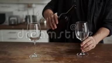 厨房里的一个年轻人<strong>把酒</strong>倒进杯子里。 浪漫的约会。 筹备会议