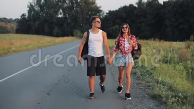 一对夫妇在度假时，沿着公路搭便车，并持有任何地方的标志。 夏日时光。 徒步旅行，游客，冒险