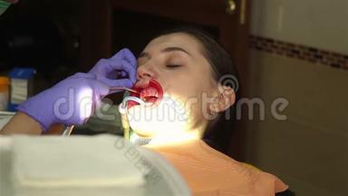 在牙科诊所有<strong>扩张</strong>器的年轻女子。 用水清洁牙齿。 现代牙科诊所。