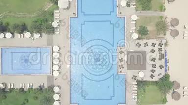 蓝色游泳池，雨伞和绿色草坪在豪华度假酒店鸟瞰.. 大型游泳池和雨伞
