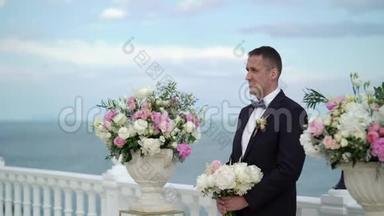 婚礼上的年轻新郎站在拱门的祭坛前等待新娘。 海边的婚礼