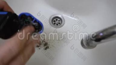 早上，男士在洗手池或洗手池中用剃须刀清洗电动旋转剃须刀