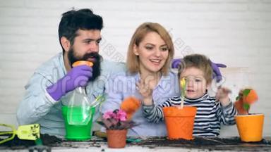 父母教男孩如何照顾花。 这家人在春天用彩色花盆种花。