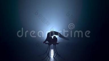 桌子上的体操运动员坐在劈叉上。 烟雾背景。 慢<strong>动作</strong>。 <strong>剪影</strong>