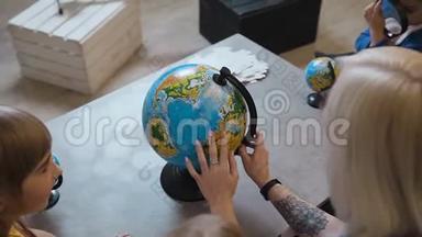 上景。 一位有纹身的时尚<strong>老师</strong>给孩子们看一个地球仪。 <strong>老师</strong>在地球上和孩子们讨论地理问题