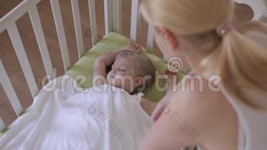 母亲抚摸一个熟睡的孩子的手。 产妇护理。 婴儿正在婴儿床上休息。