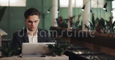 疲惫的年轻商人坐在咖啡馆里，用笔记本电脑工作。 自由，沟通，IT，疲惫的商人