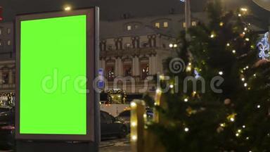 有绿色<strong>屏幕</strong>的广告牌，位于一条繁忙的街道上。 这座城市为新年装饰。 <strong>汽车</strong>在行驶