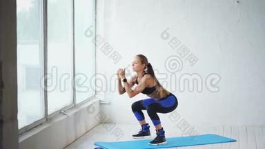 <strong>蹲下</strong>。 可爱的年轻女子<strong>蹲</strong>在健身室里。 健身房里的场景。