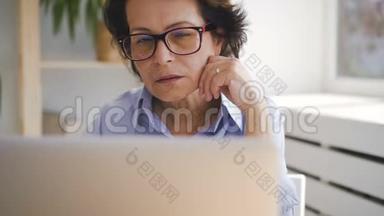 <strong>家中</strong>坐在笔记本电脑屏幕前的老年商务女士的肖像。