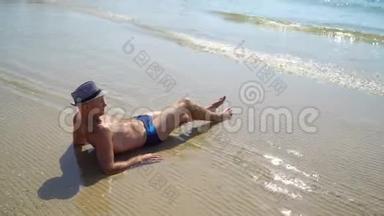<strong>夏季</strong>生活方式高清视频美丽的年轻晒黑男子戴帽子。 享受生活，坐在海滩上，旅行的时间