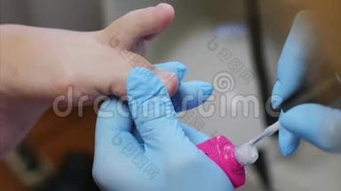 美容师用粉色皮肤紫胶在美容院涂脚趾甲。