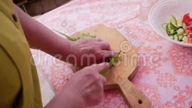 女人用刀子切菜，在切板上做沙拉。 伟大的计划。 快关门。