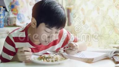 可爱的泰国男孩在客厅的白色桌子上吃炒饭。