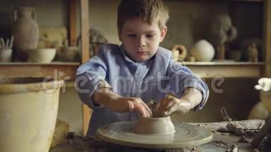 <strong>陶艺</strong>班的小男孩学生在陶工`的车轮上塑造粘土，学习传统工艺。 严重的孩子