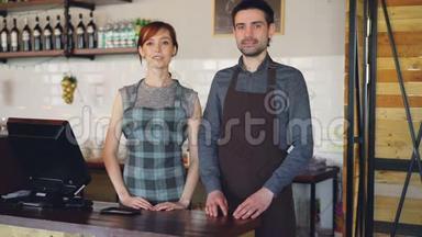 两个穿着围裙的自信的服务员站在咖啡屋的<strong>收银台</strong>`微笑的画像。 成功的业务