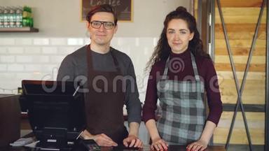 两个年轻漂亮的服务员站在咖啡屋的收银台`微笑的画像。 成功的业务