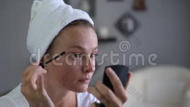 漂亮的女人正在涂睫毛膏。 女孩在脸上化妆