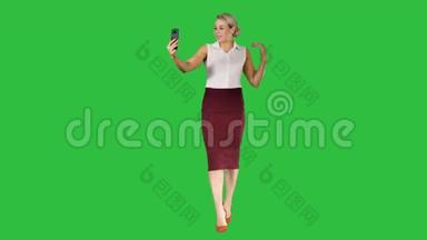 走路的女人用智能手机在绿色屏幕上打视频电话，Chroma键。