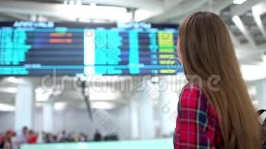 年轻微笑的女人使用智能手机检查她的航班在抵达桌背景的肖像。 乘客