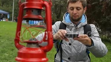 好奇的背包客在他的现代智能手机上制作稀有煤油灯的照片