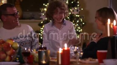 节日桌上的黄昏蜡烛。 圣诞晚餐。 孙子从桌子底下<strong>跳出</strong>来，使他吃惊
