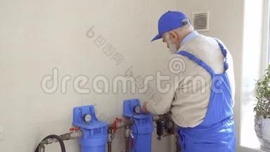 老人在蓝色工作服中修理暖气管道