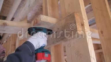 戴工作手套的人的手在木板上拧动自攻。拧进木头