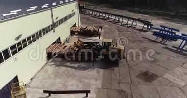 推土机在一家木工工厂的输送机上卸下<strong>原木</strong>。 载有<strong>原木</strong>的黄色推土机