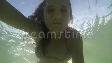 漂亮的年轻快乐的女人在热带海洋中通过太阳在水下游泳。 慢动作。 1920x1080
