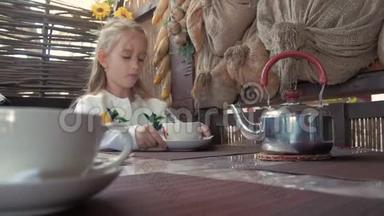 可爱的小女孩在咖啡馆喝茶。 清淡的早餐。 小白种人女孩在咖啡馆喝茶。