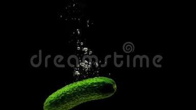 绿色黄瓜在黑色背景下落入透明水