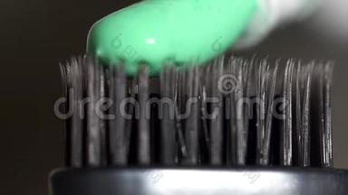 在深灰色背景下，用绿色牙膏从试管中挤出来的灰色牙刷，牙齿