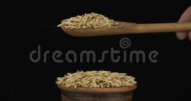 燕麦颗粒从一个木勺上得到足够的睡眠，在一堆泥土碗里的种子。